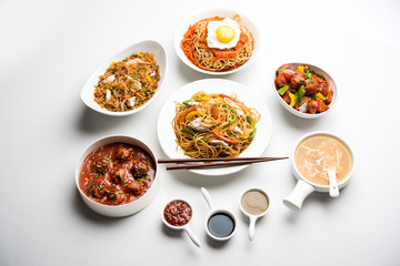 Assorted Indo chinese food in group includes non vegetarian or chicken Schezwan/Szechuan hakka noodles, fried rice, manchurian, egg american chop suey, soup with spoon and chop sticks, selective focus