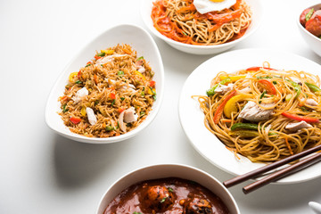 Assorted Indo chinese food in group includes non vegetarian or chicken Schezwan/Szechuan hakka noodles, fried rice, manchurian, egg american chop suey, soup with spoon and chop sticks, selective focus