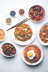 Assorted Indo chinese food in group includes non vegetarian or chicken Schezwan/Szechuan hakka noodles, fried rice, manchurian, egg american chop suey, soup with spoon and chop sticks, selective focus