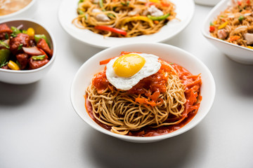 Assorted Indo chinese food in group includes non vegetarian or chicken Schezwan/Szechuan hakka noodles, fried rice, manchurian, egg american chop suey, soup with spoon and chop sticks, selective focus