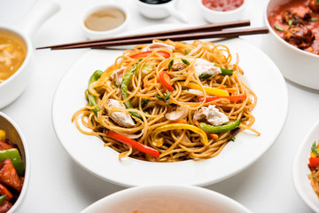 Assorted Indo chinese food in group includes non vegetarian or chicken Schezwan/Szechuan hakka noodles, fried rice, manchurian, egg american chop suey, soup with spoon and chop sticks, selective focus