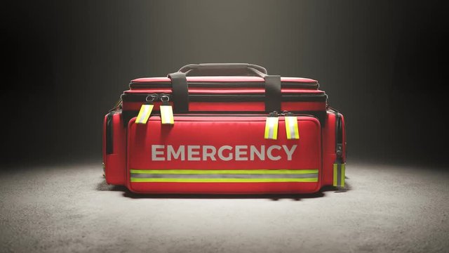 The red emergency first aid bag in the studio spotlight. Paramedic kit. 4KHD
