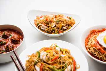 Assorted Indo chinese food in group includes non vegetarian or chicken Schezwan/Szechuan hakka noodles, fried rice, manchurian, egg american chop suey, soup with spoon and chop sticks, selective focus