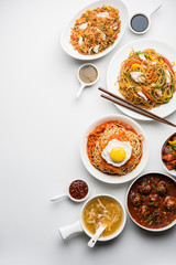 Assorted Indo chinese food in group includes non vegetarian or chicken Schezwan/Szechuan hakka noodles, fried rice, manchurian, egg american chop suey, soup with spoon and chop sticks, selective focus