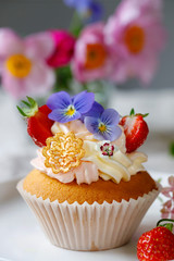 Cupcake decorated with buttercream, fruits and flowers