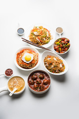 Fototapeta na wymiar Assorted Indo chinese food in group includes non vegetarian or chicken Schezwan/Szechuan hakka noodles, fried rice, manchurian, egg american chop suey, soup with spoon and chop sticks, selective focus