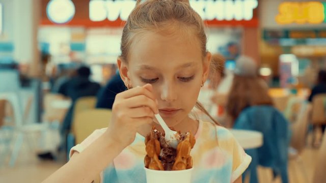 Cute teenager girl eating ice cream in food court. Young girl teenager enjoying ice cream dessert in shopping mall cafe. Fast food and dessert food concept
