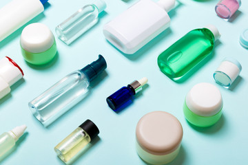 Top view of cosmetic products in different jars and bottles on blue background. Close-up of containers with copy space