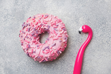 Pink doughnut and Flamingo pen on a grey background. Top view Flat lay.