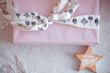wooden star with the inscription merry christma s and a gift in pink packaging. Top view