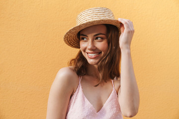 Photo closeup of pleased young woman wearing summer straw hat smiling and looking aside