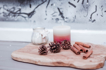 New Year's decor of fir cones, cinnamon sticks and candles on the windowsill
