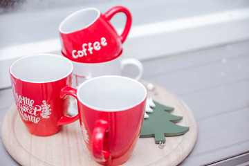 Red cups stand on a wooden stand on the windowsill