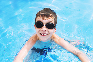 happy baby in the pool. boy swims in the pool with swimming glasses. . boy learning to swim