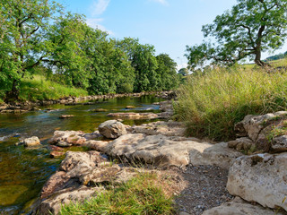 The River Ribble flowing gently through meadows near the village of Little Stainforth in the Yorkshire Dales
