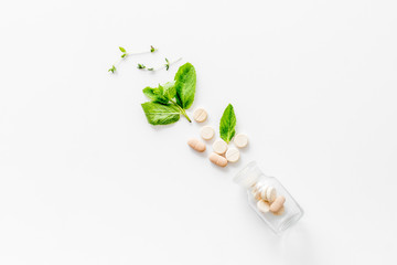 Homeopathy with pills, leaves and healing herbs on white background top view copyspace