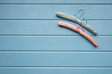 Two clothes hangers lie on a blue wooden background. The concept of minimalism. View from above, a place for text.