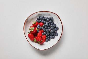 top view of big plate with delicious blueberries and strawberries