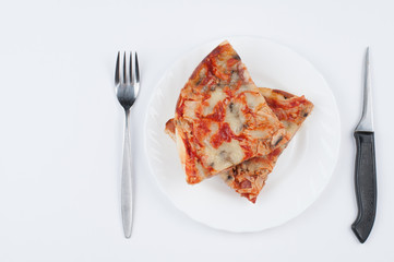 A delicious homemade pizza on a plate isolated on a white background. Pizza on a plate with a knife and a fork