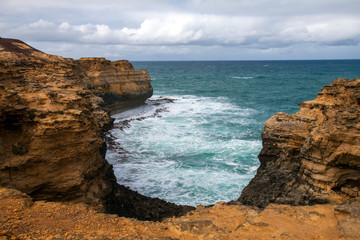 Rugged, barren looking coastal scene with turbulent waters  and a grey, stormy sky.