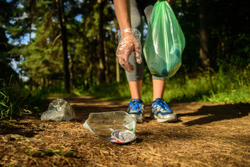 Woman collecting garbage in forest