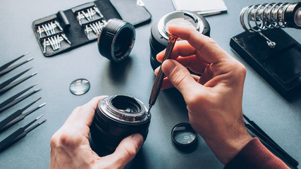 Electronic device service. Top view of man hands repairing photo camera optical dslr lens.