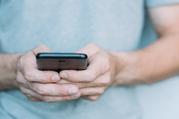 Mobile technical service. Closeup of man hands holding smartphone, texting message. Copy space.