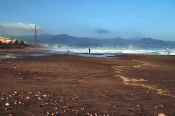Beach during a storm in Malaga on a sunny day on the background of mountains and the city