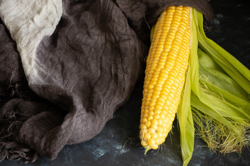Homemade fresh corn with leaves. Bright, yellow. On a dark background.