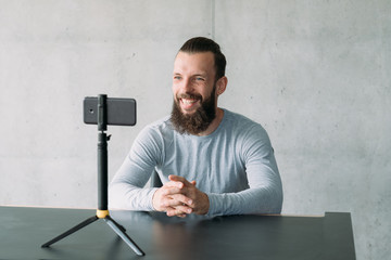 Modern business coaching. Confident hipster guy using smartphone camera to record speech video. Copy space.