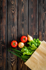 Buying fresh vegetables in paper bag on wooden background top view copyspace