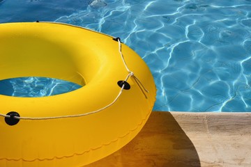 Yellow pool float, ring floating lying by the refreshing swimming pool. Close up, detailed view....