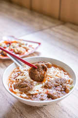 Beef noodle - Taiwan ramen meal with tomato sauce broth in bowl on bright wooden table, famous chinese style food, close up, top view, copy space