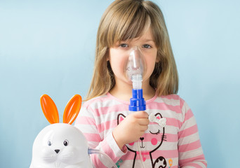 Cute toddler girl having inhalation for easy cough at home. Allergy and health care concept. Copy...