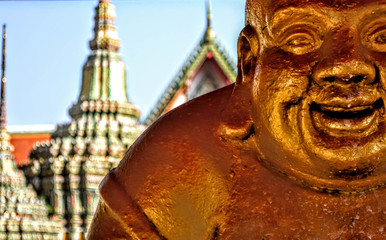 buddah gordo de bronce con templo de fondo 