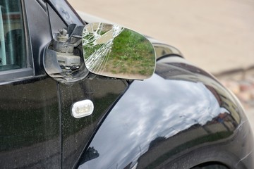 Road accident.  Black car with a broken side mirror. Crushed automobile side view mirror. Parked auto with breakdown glass. Car vandalism. 