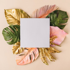 Creative layout made of colorful and golden tropical leaves and palms on beige background. Minimal summer exotic concept with copy space. Border arrangement background.