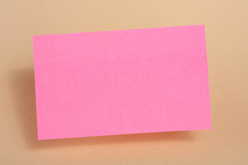 Pink paper sticker for text hanging in the air on a beige background. Blank or template.