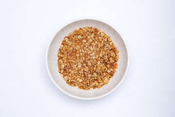 Muesli with banana in a white bowl on gray (white) background