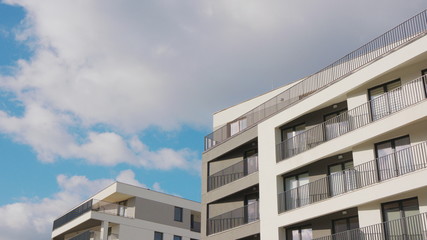 Obraz premium White clouds floating in the blue sky over a block of flats.