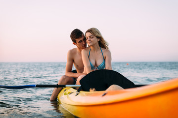 Vacation on the ocean, lovers newlyweds kayaking, hugs and passion.