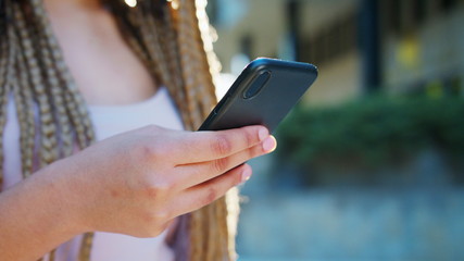 A young lady using a phone outdoors. Close-up shot