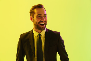 Image of excited young businessman in formal suit smiling and rejoicing