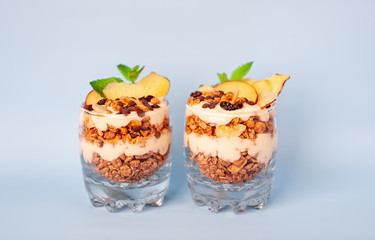 two parfaits of granola, yogurt, fresh peach, banana chips, mint, healthy breakfast