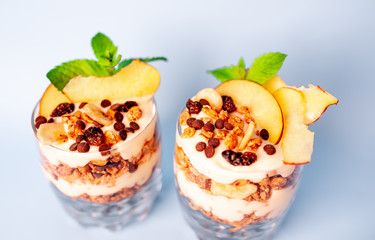 two parfaits of granola, yogurt, fresh peach, banana chips, mint, healthy breakfast