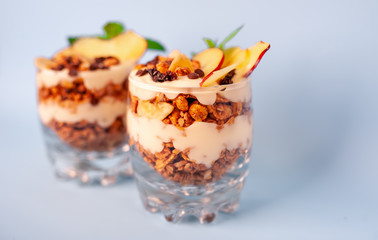 two parfaits of granola, yogurt, fresh peach, banana chips, mint, healthy breakfast