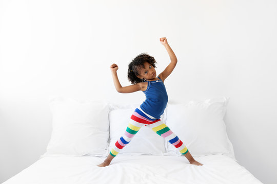 Energetic little girl dancing on white bed