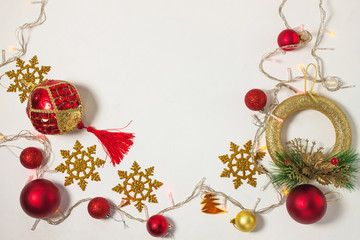 Christmas present box with red ribbon, gold decorations, balls, snowflakes and lights on a white background.