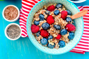 High protein healthy breakfast, buckwheat porridge with blueberries, raspberries, flax seeds and honey Closeup view, selective focus