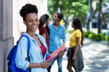 Laughing african american female student in front of university